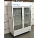 Right angled perspective view of a VWR double door chromatography refrigerator featuring its white housing, glass doors with vertical handles, internal wire shelving, side panel ports, and lower grill panel