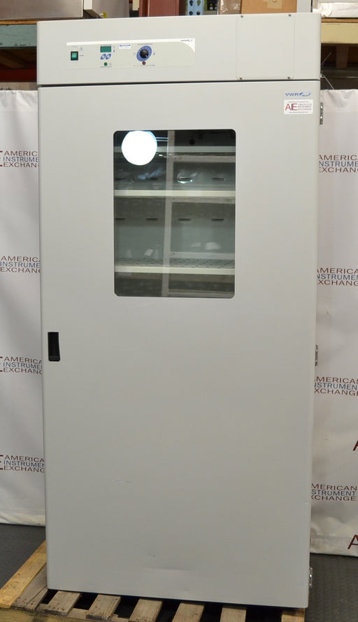 Front eye-level view of a VWR Model 1925 reach-in incubator resting on a wooden pallet, featuring a tall solid door with a central glass viewing window, top-mounted digital and analog control panel, and internal wire shelving