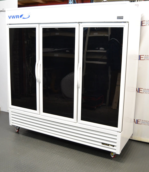 Front eye-level view of a VWR triple glass door laboratory refrigerator on locking casters, featuring a white cabinet body, three black-tinted glass doors with upright white handles, upper VWR branding, and a louvered bottom grille