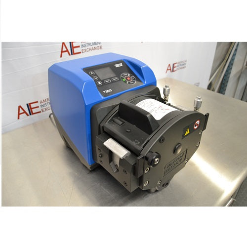 Left angled perspective view of Watson Marlow 730UN peristaltic process pump on a stainless steel bench showing blue drive unit housing, digital control keypad, and front pump head mechanism