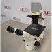 Front angled view of Zeiss Primovert inverted microscope featuring binocular viewing eyepieces, black specimen stage, focusing knob, and overhead illumination column