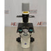 Slight high-angle front view of Zeiss Primovert inverted microscope showing binocular eyepieces, black specimen stage platform, slider condenser mount, and vertical condenser arm