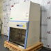 An alternative angled view of a Thermo Scientific 1342 biosafety cabinet secured on a wooden pallet, showing its side profile, closed protective sash window, and digital control panel housing.