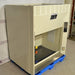 An angled view of a Kewaunee chemical fume hood mounted on a blue pallet, showing its side housing panel, workspace interior with service valves, and vertical sash opening.