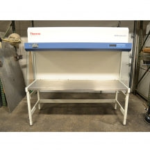 A front-facing view of a Thermo Heraguard ECO 1.8 laminar flow clean bench, showing its wide stainless steel work surface, open front workspace, side glass panels, and upper control console.
