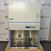 A front-facing view of a Thermo Scientific 1342 biosafety cabinet resting on a wooden pallet, showing its stainless steel interior workspace, digital control display panel, and blue and white exterior housing.